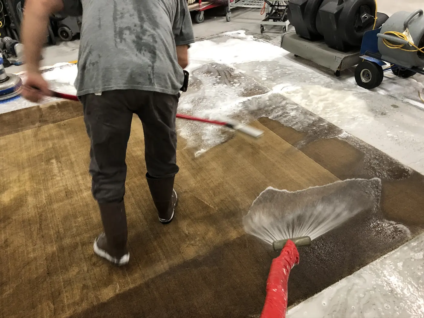 Sheet of clean water flushing shampoo and soil out of a rug during rinsing